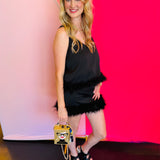 Side profile of the black feather cami paired with a purse, highlighting the feather trim, sleeveless fit, and flattering silhouette