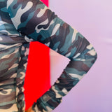 Close-up of the sleeve on the Keigan Mesh Top showing the green camo print, soft stretch mesh fabric, and delicate lettuce-edge hem detail.