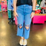 close up of Blackberry colored washed cropped jeans with distressed knees and raw hem