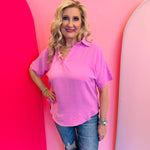 Candy pink collared V-neck airflow top with short sleeves and a relaxed, flowy fit.