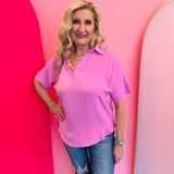Candy pink collared V-neck airflow top with short sleeves and a relaxed, flowy fit.