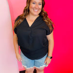 Black woven blouse with V-neckline and cuffed short sleeves.
