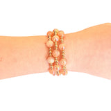Water resistant blush pink beaded elastic bracelet with pearlescent beads and gold spacer accents.