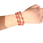 Water resistant burgundy beaded elastic bracelet with pearlescent beads and gold spacer accents.