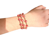 Water resistant burgundy beaded elastic bracelet with pearlescent beads and gold spacer accents.