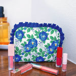 Blue floral quilted bag with ruffle trim and zipper closure.