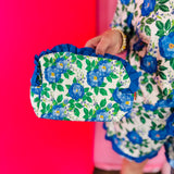 Blue floral quilted bag with ruffle trim and zipper closure.