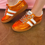 Orange metallic Corky's sneakers with white side stripes and lace-up closure.