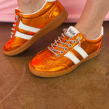 Orange metallic Corky's sneakers with white side stripes and lace-up closure.