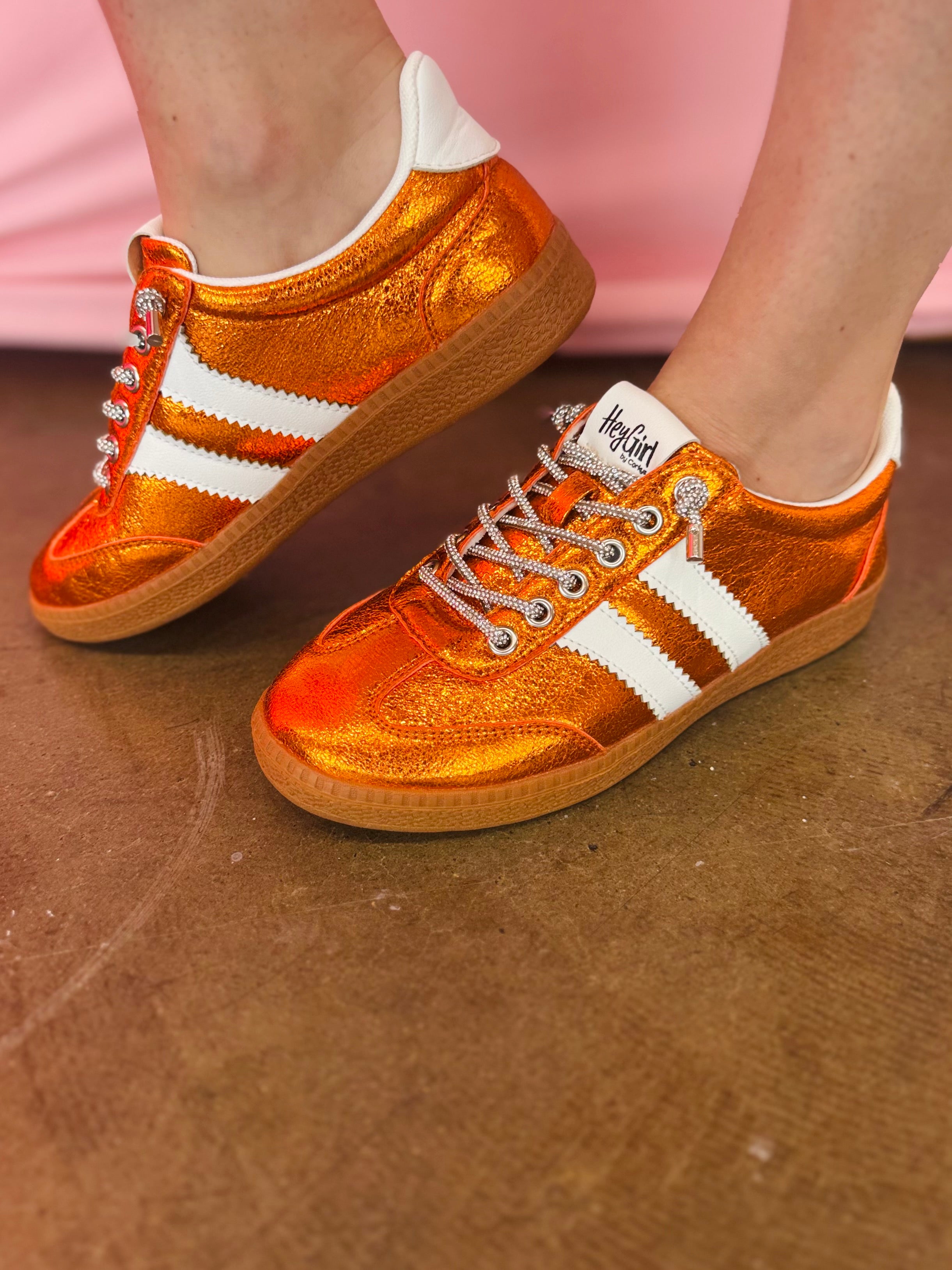 Orange metallic Corky's sneakers with white side stripes and lace-up closure.