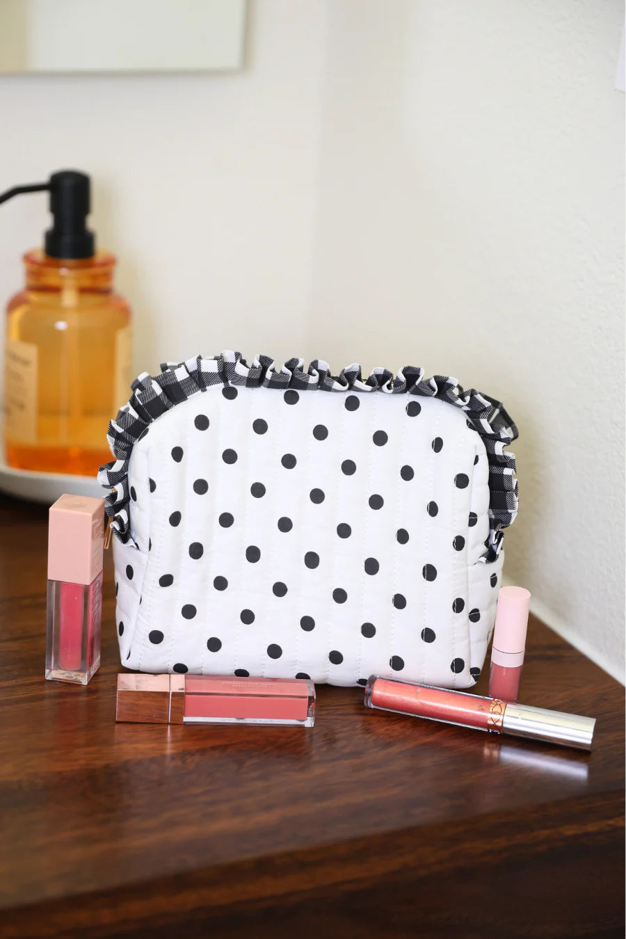 Black and white polka dot quilted bag with gingham ruffle trim and zipper closure.