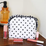 Black and white polka dot quilted bag with gingham ruffle trim and zipper closure.