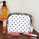 Black and white polka dot quilted bag with gingham ruffle trim and zipper closure.