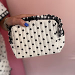 Black and white polka dot quilted bag with gingham ruffle trim and zipper closure.