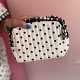 Black and white polka dot quilted bag with gingham ruffle trim and zipper closure.