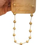 Dainty gold necklace with polished bead accents on a textured, water-proof chain.