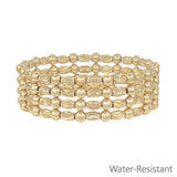 Gold textured oval and gold beaded set of four water resistant stretch bracelets stacked.
