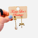 Gold bow earrings with chain drops and pearl accents asymmetrical design