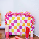 Checkerboard quilted bag with floral ruffle trim and zipper closure.