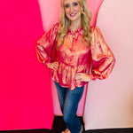 Fuchsia metallic bow peplum top with long sleeves and U-neckline for a festive, elegant look.
