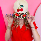 Tan hat with embroidered cherry and leopard cherry patterned bill.
