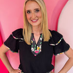 Daisy and polka dot blouse with flutter sleeves and feminine silhouette.