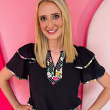 Daisy and polka dot blouse with flutter sleeves and feminine silhouette.