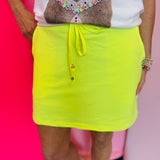 Solid skort with elastic back waistband, drawstring, built-in shorts, and side pockets.