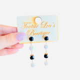 Black and pearl drop earrings linked by delicate gold chains.