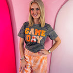 Orange Game Day tee with patchwork appliqué lettering and mixed print details.