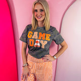 Orange Game Day tee with patchwork appliqué lettering and mixed print details.