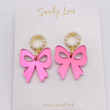 Pink acrylic bow earrings with pearl-beaded hoop studs