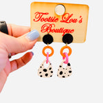Black stud earrings with orange pink links and spotted black white drops.