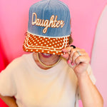 Poppy and Pine Denim-blue “Daughter” hat with brown polka dot bill, cream trim, and “of the King” side embroidery.