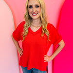 Red corded rib knit top with relaxed fit and hi-low V-neck.