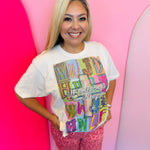 Neutral WWJD graphic tee with colorful patchwork letters and “He Would Love First” message, 100% cotton.