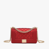 Wine quilted vegan leather crossbody bag with gold chain strap and studded detailing.