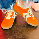 Orange lace-up sneaker with suede-look upper, cream laces, and retro low-top design.