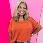 Burnt orange corded rib knit top with hi-low V-neck and short sleeves