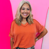Burnt orange corded rib knit top with hi-low V-neck and short sleeves