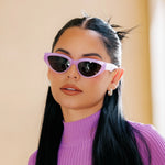 A woman wearing lavender-colored cat-eye polarized sunglasses with a purple top.